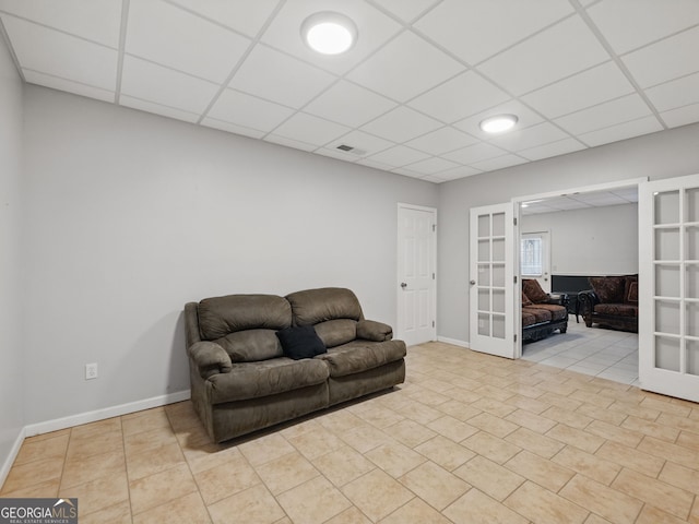 living area with french doors, a drop ceiling, and tile patterned floors