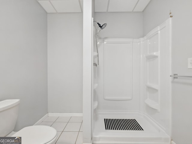 bathroom with a paneled ceiling, a stall shower, toilet, and tile patterned floors