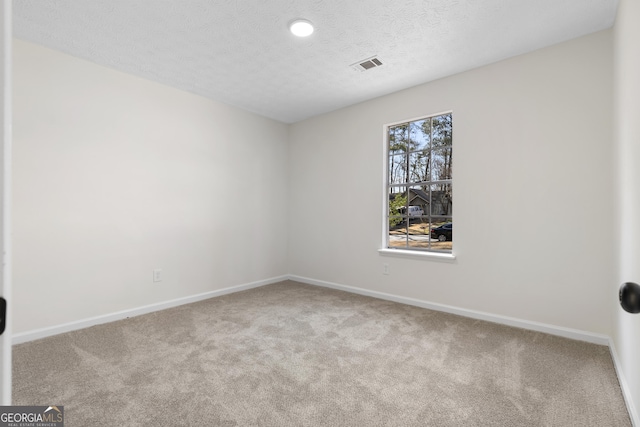 unfurnished room featuring baseboards, carpet, visible vents, and a textured ceiling