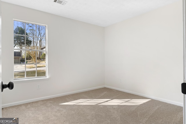 spare room featuring baseboards, visible vents, and carpet flooring