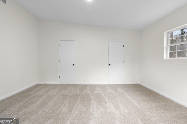 unfurnished room with light carpet and baseboards