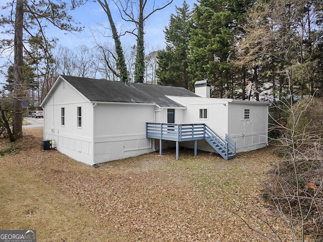 view of front facade with cooling unit, a shingled roof, crawl space, a wooden deck, and a chimney