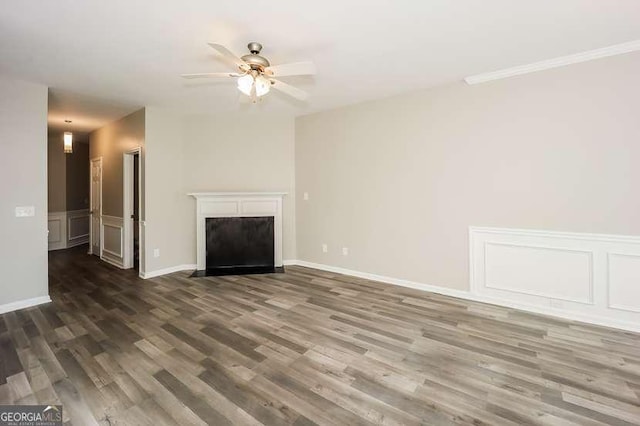 unfurnished living room featuring a fireplace with flush hearth, wainscoting, a decorative wall, and wood finished floors