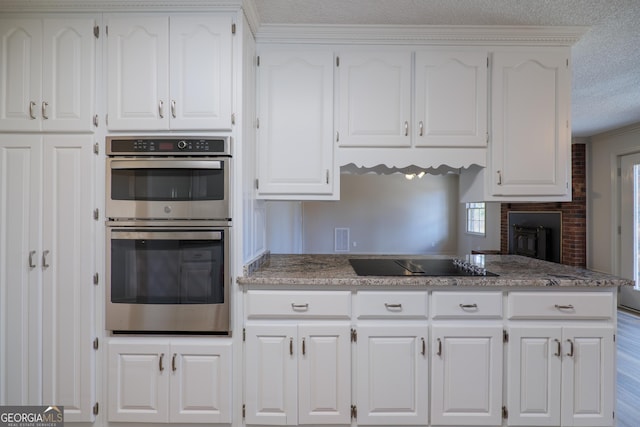 kitchen with stainless steel double oven, white cabinets, and black electric cooktop