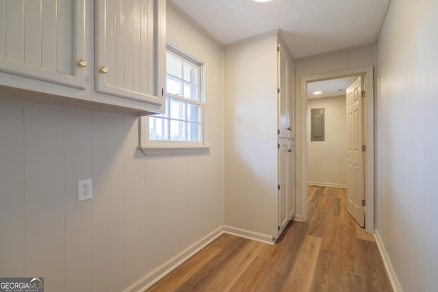 hallway featuring light wood-type flooring, baseboards, and a textured ceiling