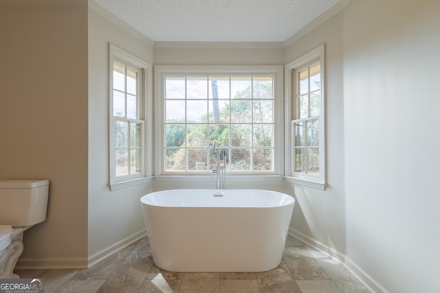 bathroom featuring a freestanding tub, baseboards, a textured ceiling, and toilet