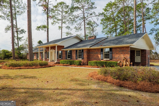 view of front of home featuring brick siding, a chimney, and a front yard