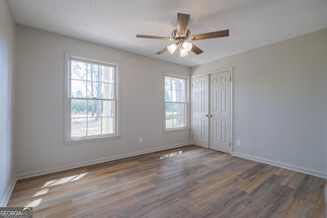 spare room featuring a textured ceiling, a wealth of natural light, and wood finished floors