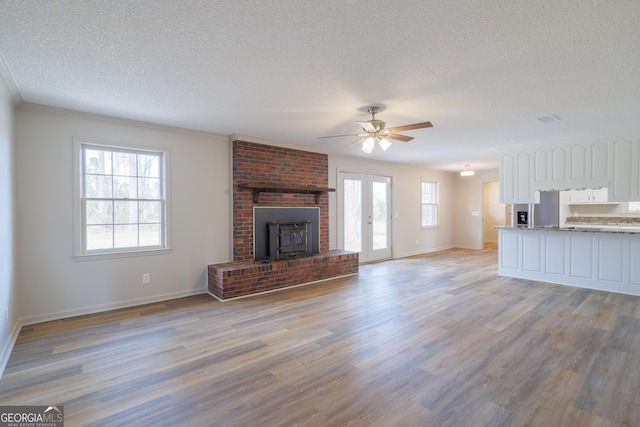 unfurnished living room featuring a textured ceiling, baseboards, and light wood-style floors