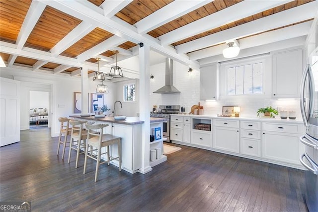 kitchen with a breakfast bar, white cabinets, appliances with stainless steel finishes, wall chimney exhaust hood, and dark wood finished floors