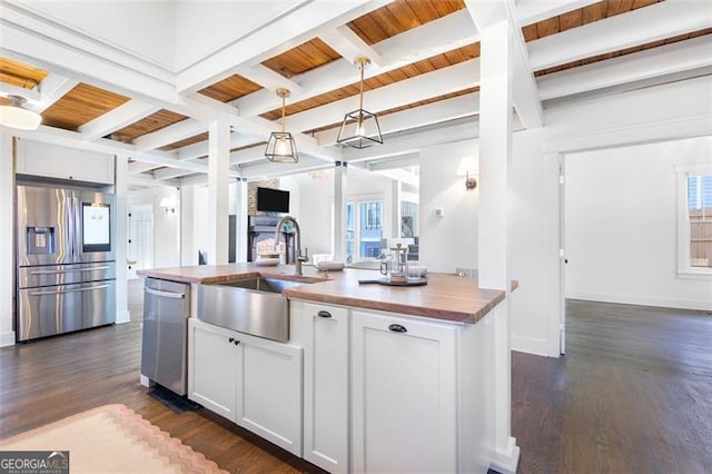 kitchen featuring open floor plan, beamed ceiling, dark wood-style flooring, stainless steel appliances, and a sink