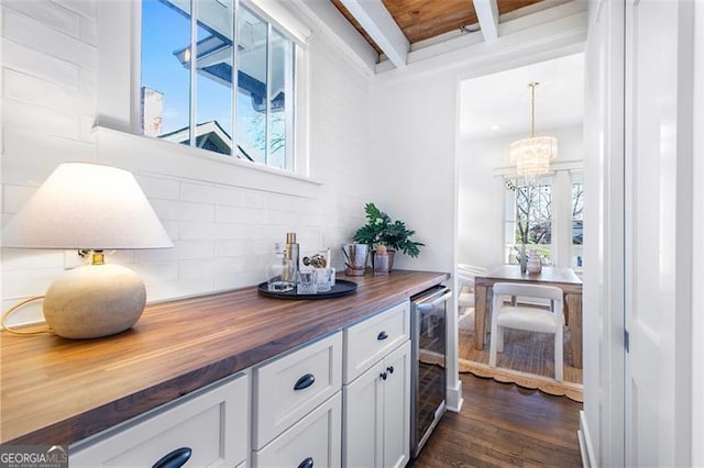 bar featuring beam ceiling, dark wood finished floors, backsplash, a chandelier, and beverage cooler