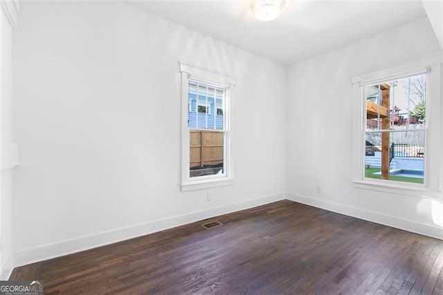 spare room with visible vents, baseboards, and dark wood-style flooring