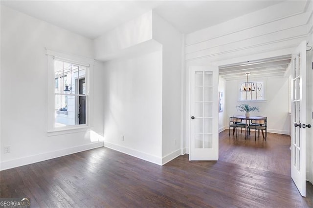 empty room featuring french doors, a notable chandelier, and dark wood-style flooring