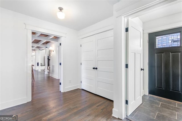 foyer entrance featuring dark wood-type flooring, beam ceiling, coffered ceiling, and baseboards