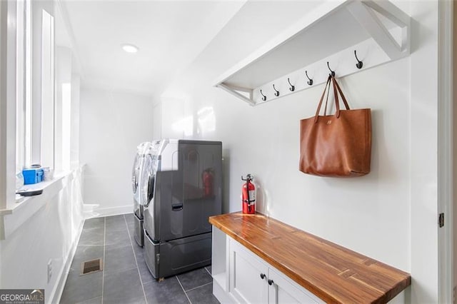 laundry area with laundry area, dark tile patterned flooring, washing machine and dryer, and visible vents