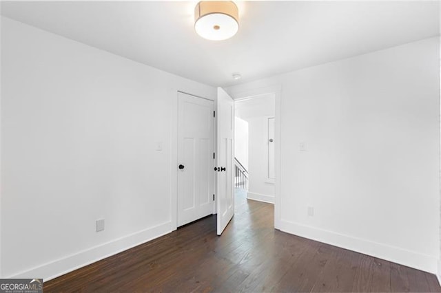 empty room with dark wood-style flooring and baseboards