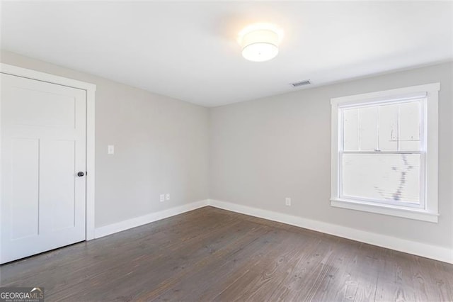 spare room with visible vents, dark wood finished floors, and baseboards