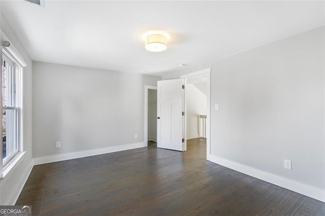 empty room featuring dark wood-style flooring and baseboards