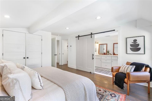 bedroom with ensuite bathroom, a barn door, recessed lighting, wood finished floors, and beamed ceiling