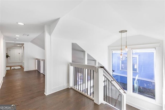 hallway with baseboards, vaulted ceiling, dark wood-type flooring, and an upstairs landing