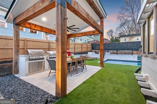 yard at dusk featuring an outdoor kitchen, outdoor dining area, a patio area, and a fenced backyard