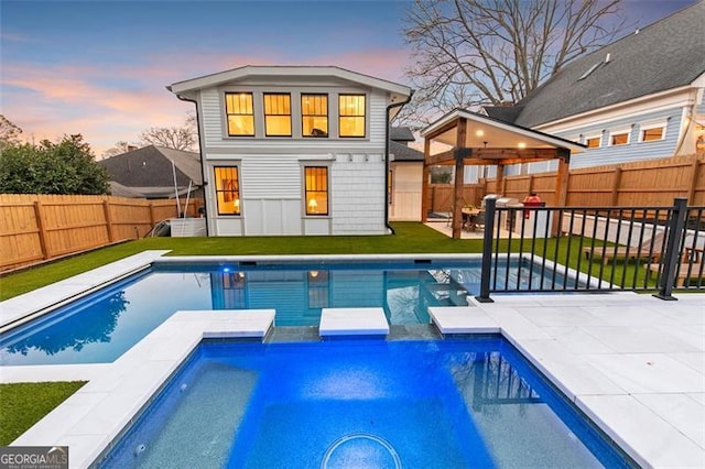 rear view of property featuring a yard, a patio, a fenced backyard, and a pool with connected hot tub