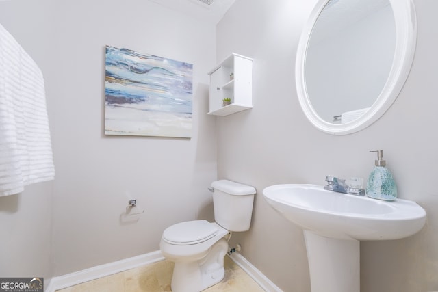 half bathroom with tile patterned floors, toilet, and baseboards