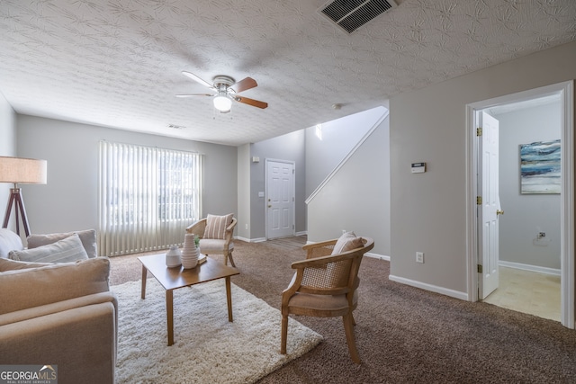 carpeted living area with baseboards, a textured ceiling, visible vents, and a ceiling fan