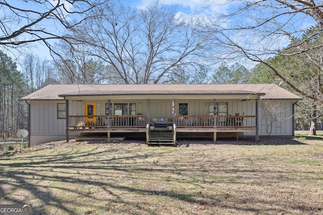 rear view of property featuring board and batten siding, a yard, and roof with shingles