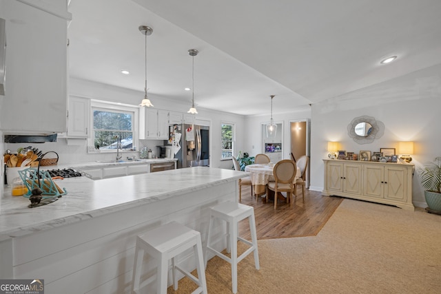 kitchen with a breakfast bar, a peninsula, a sink, hanging light fixtures, and stainless steel appliances