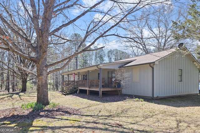 rear view of house with a yard, covered porch, and roof with shingles