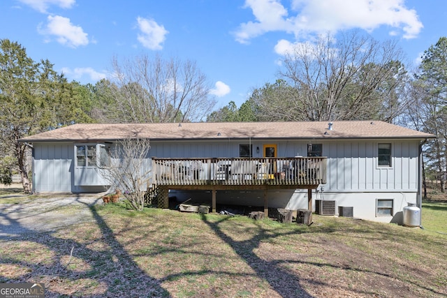 rear view of property with central AC unit, a lawn, board and batten siding, and a wooden deck