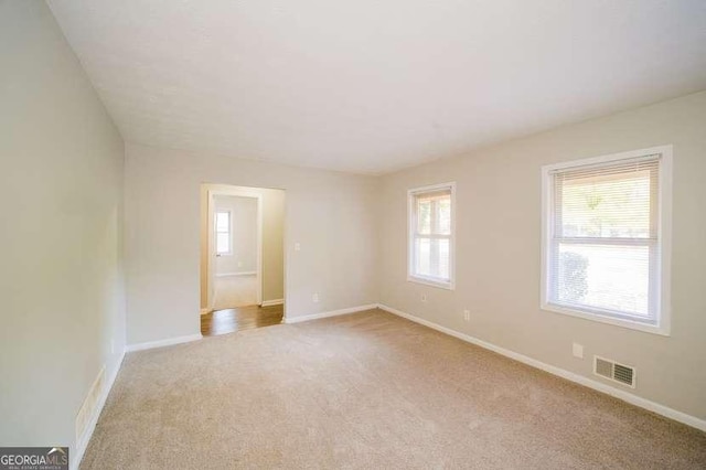 empty room featuring a wealth of natural light, carpet, and baseboards