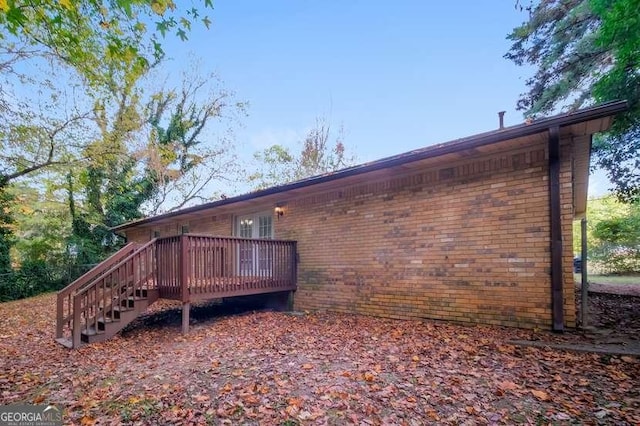 view of property exterior featuring brick siding and a wooden deck