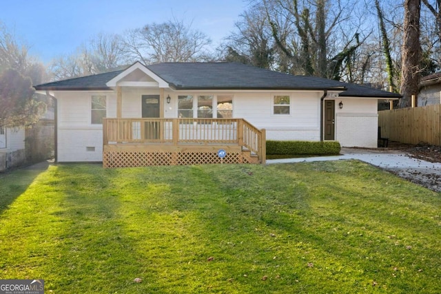 exterior space with brick siding, fence, a deck, and a lawn