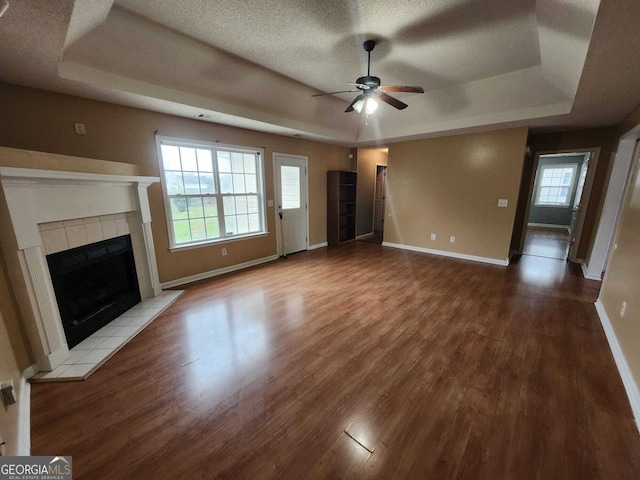 unfurnished living room featuring a raised ceiling, a fireplace, and wood finished floors