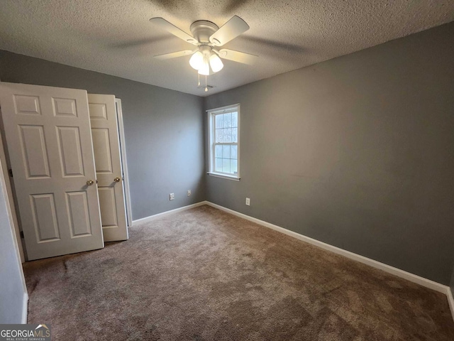 unfurnished bedroom featuring carpet flooring, ceiling fan, a textured ceiling, and baseboards