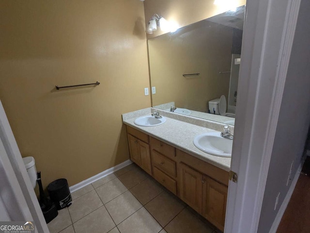 bathroom with toilet, double vanity, a sink, and tile patterned floors