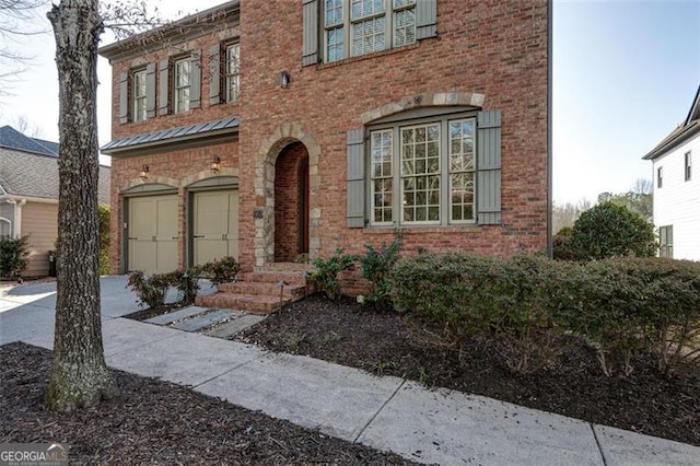 view of front facade featuring a garage, metal roof, and brick siding