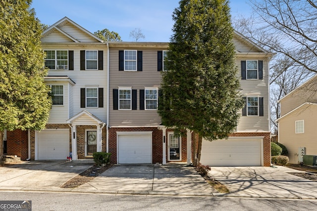 multi unit property featuring driveway, central air condition unit, an attached garage, and brick siding