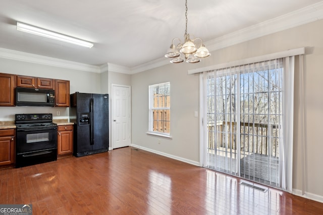 kitchen with dark wood-type flooring, visible vents, light countertops, black appliances, and crown molding