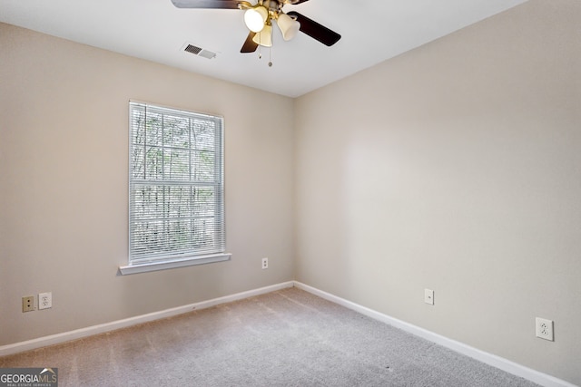 carpeted spare room with a ceiling fan, visible vents, and baseboards