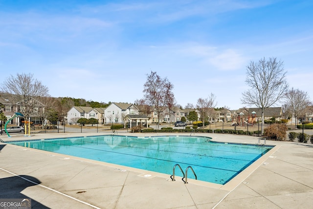 pool featuring playground community, a patio area, fence, and a residential view