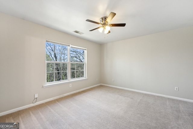 spare room with baseboards, visible vents, ceiling fan, and light colored carpet