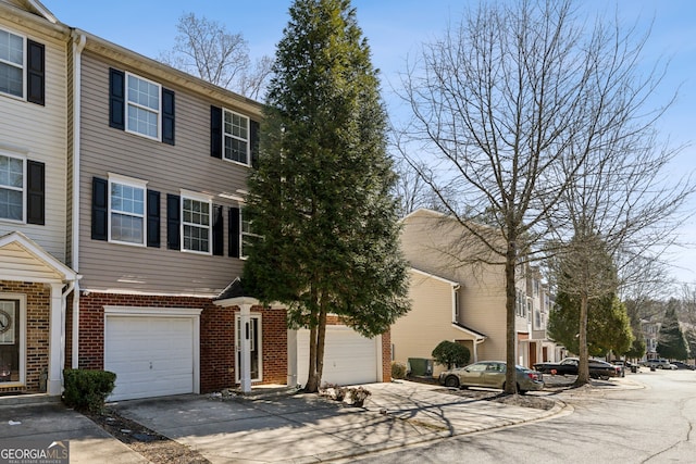 multi unit property featuring a garage, concrete driveway, and brick siding