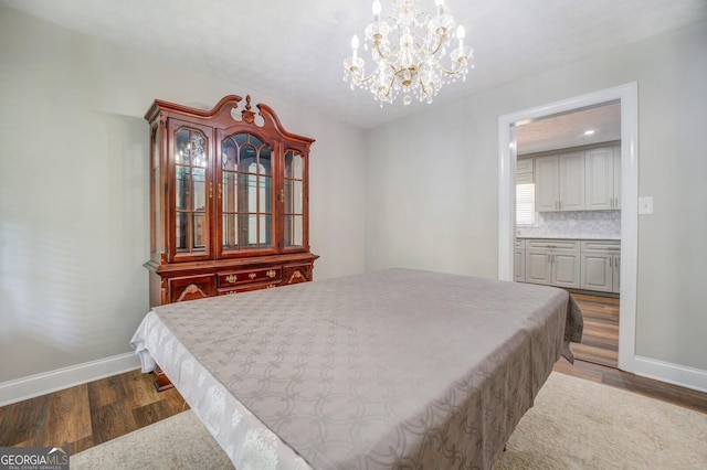 bedroom featuring a notable chandelier, dark wood-style flooring, and baseboards