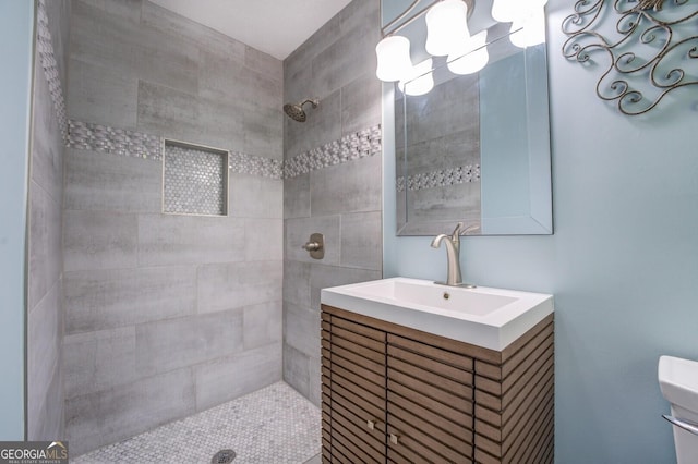 full bath with toilet, a tile shower, and vanity