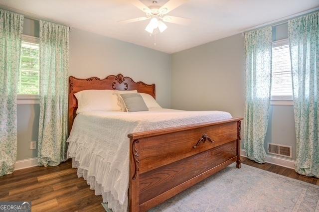 bedroom with baseboards, visible vents, ceiling fan, and wood finished floors