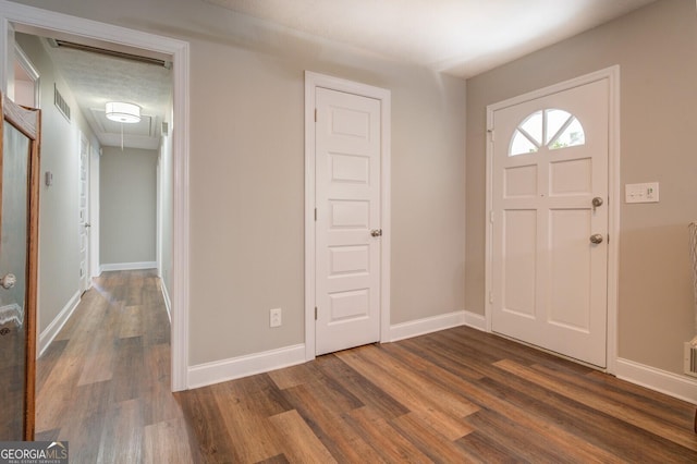 entryway with dark wood-style flooring, visible vents, and baseboards